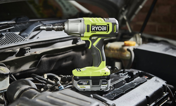 Klucz akumulatorowy udarowy RYOBI na tle silnika samochodowego